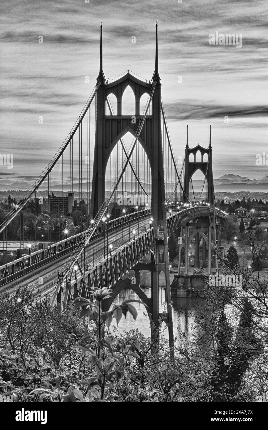 A monochrome image of a train crossing a river on a bridge Stock Photo