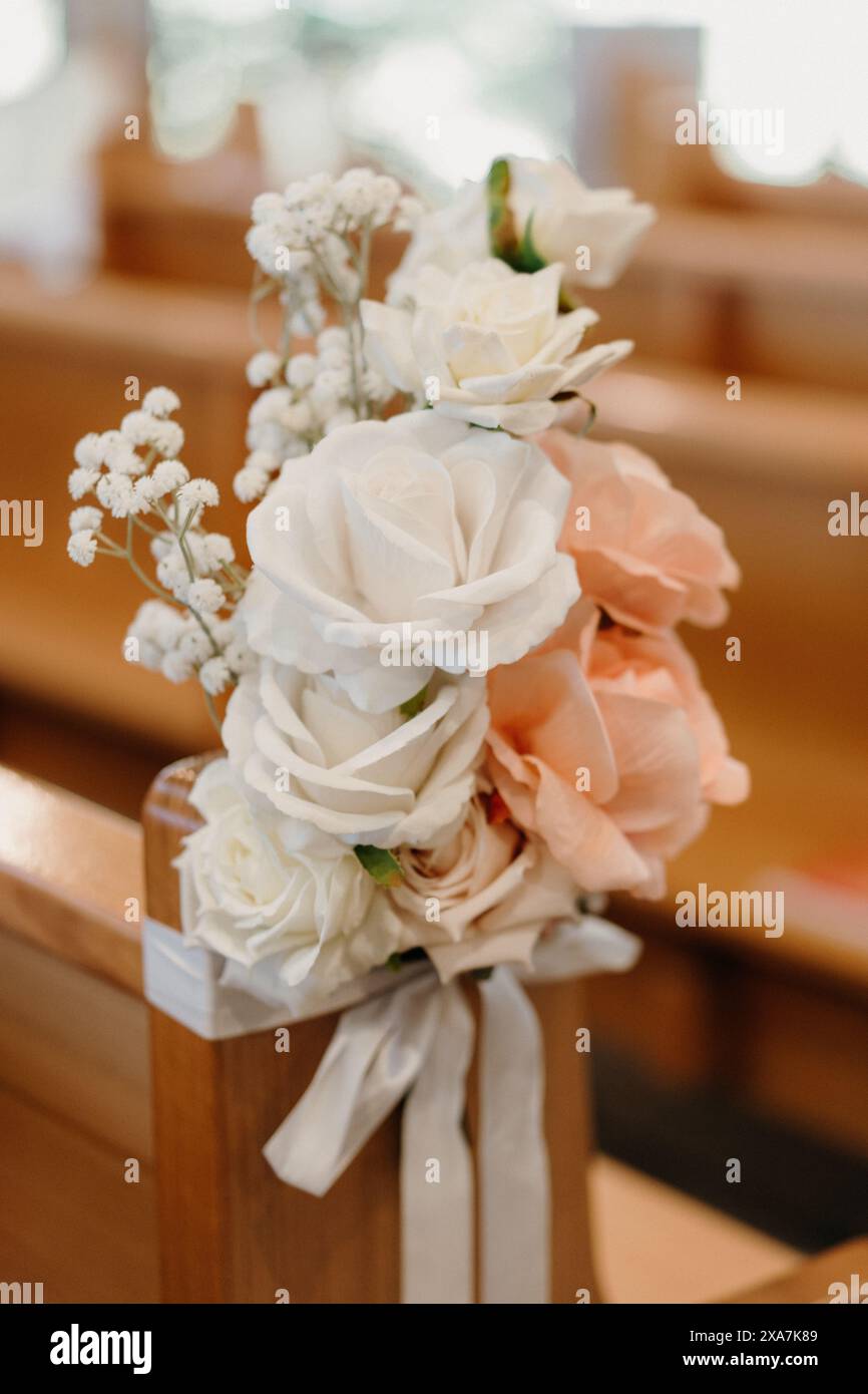 Floral arrangement adorns wooden church pew Stock Photo