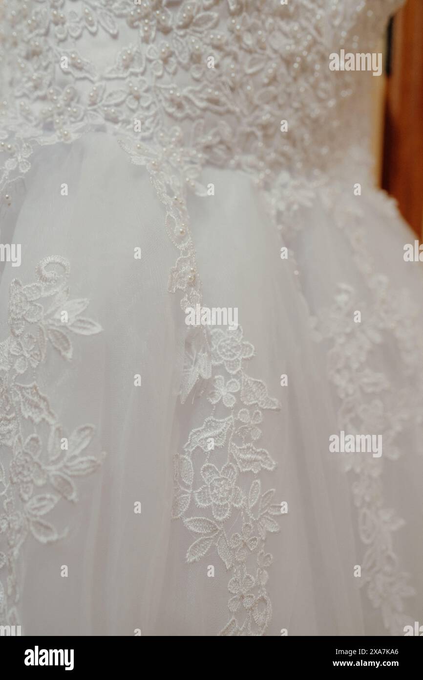 Elegant bridal gown hanging against wooden backdrop Stock Photo