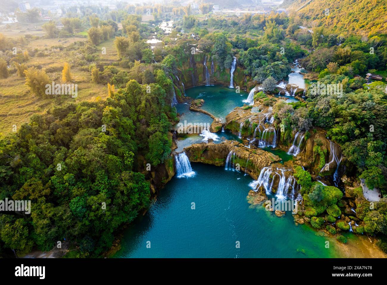 Two waterfalls next to a row of trees in a tranquil landscape Stock Photo