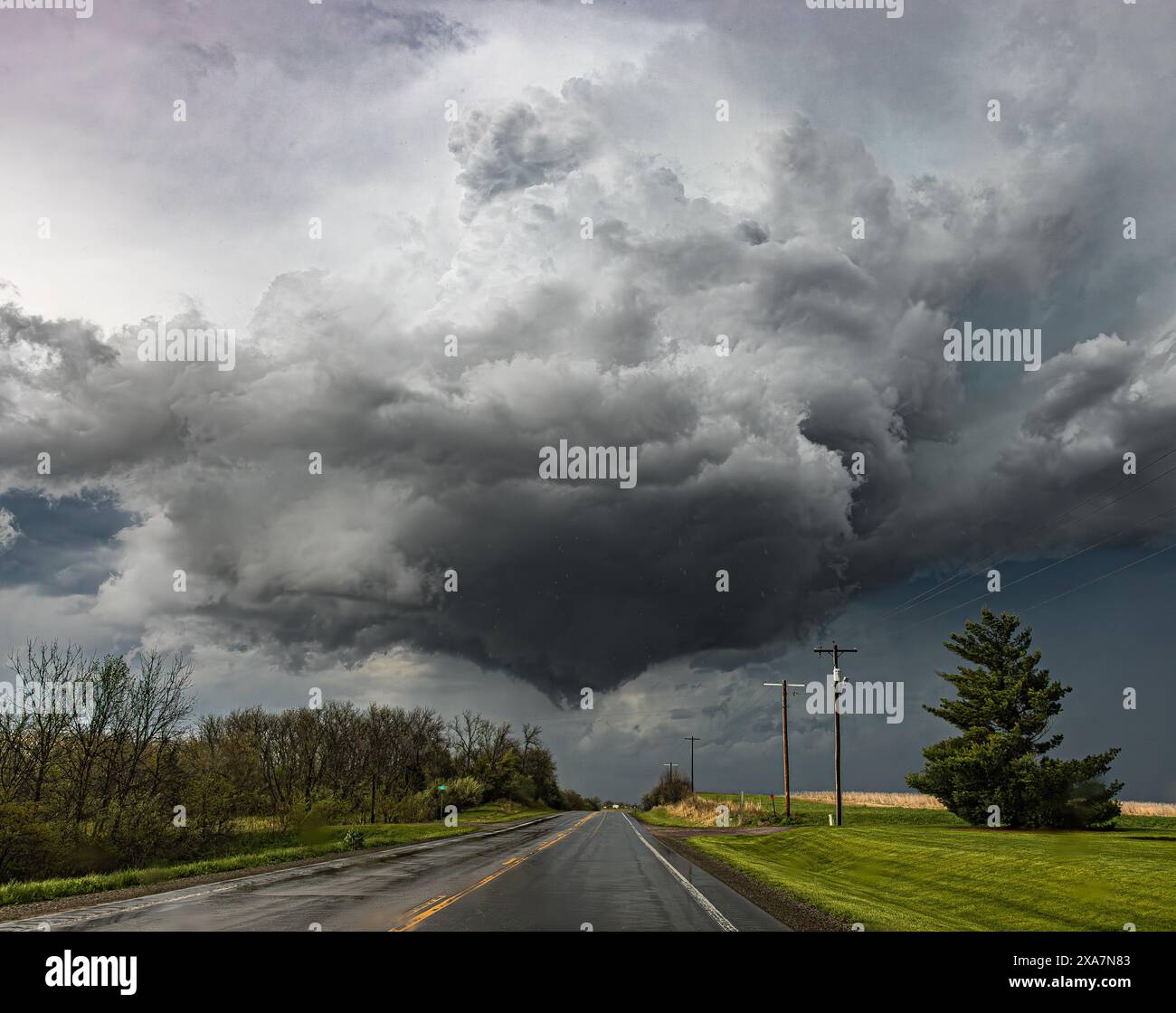 Dark clouds loom over a deserted road under a grey sky Stock Photo