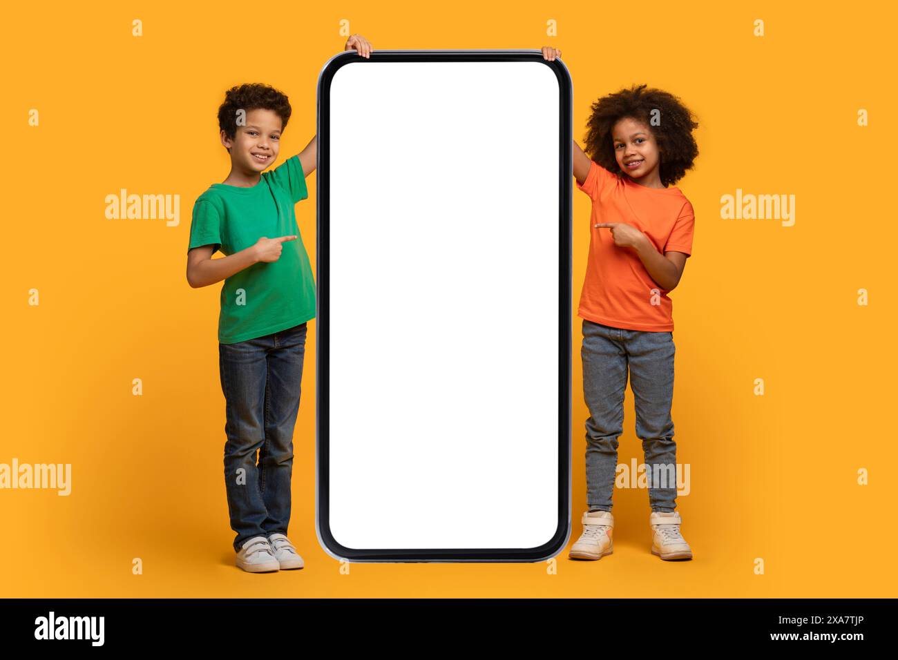 Two Children Pointing at Giant Smartphone on Yellow Background Stock Photo