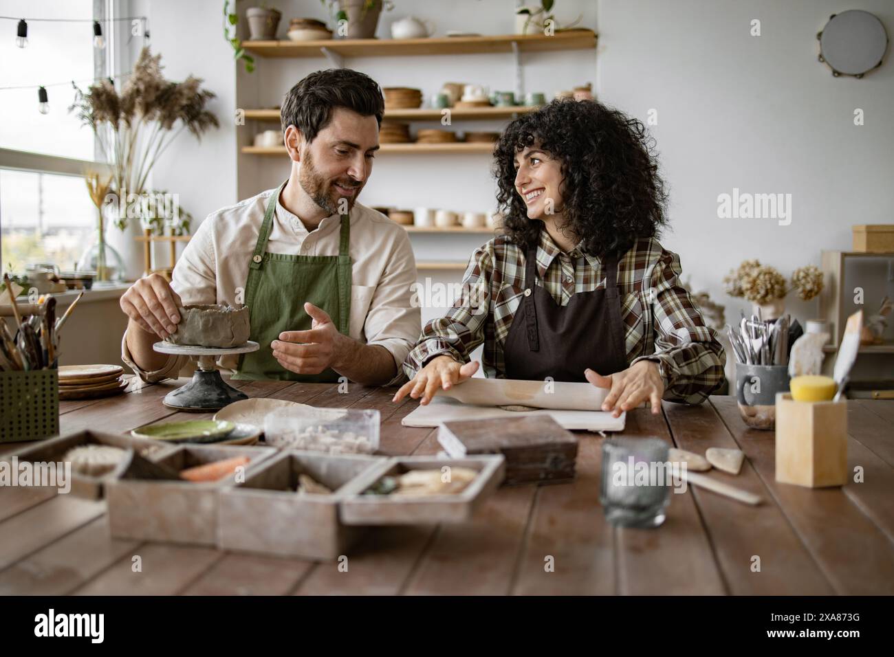 Mature man and woman sculpting clay together in pottery workshop Stock ...