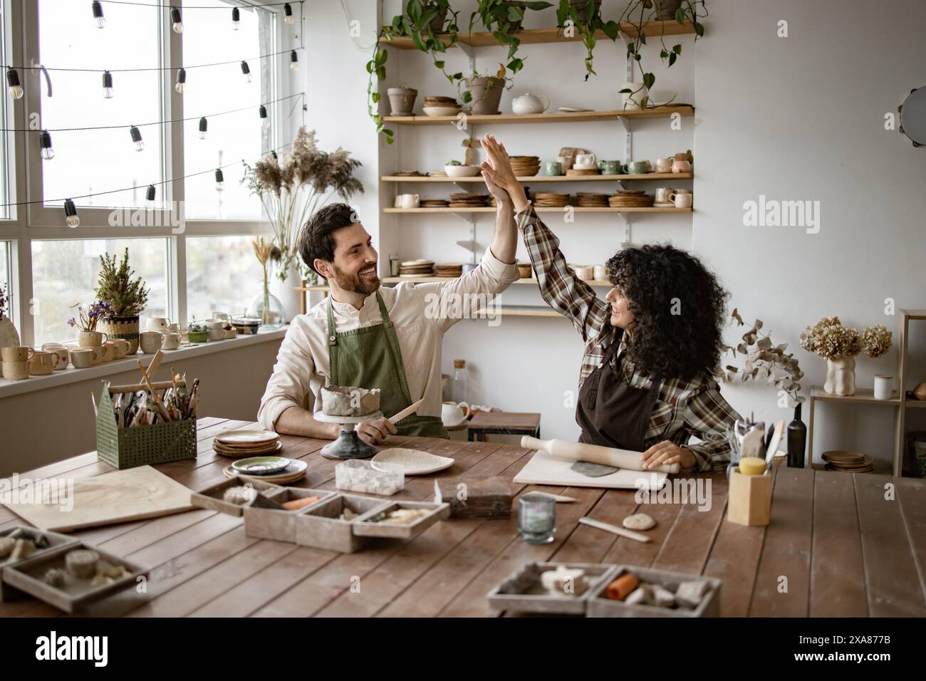 Happy pottery artists giving high five in creative studio Stock Photo ...