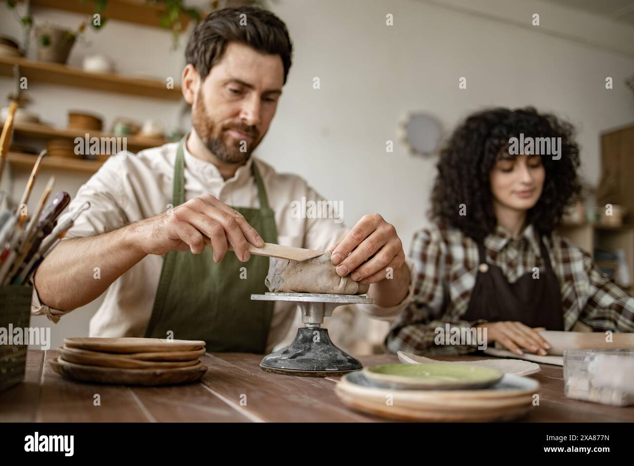 Bearded mature man and woman sculpting clay in pottery studio Stock ...