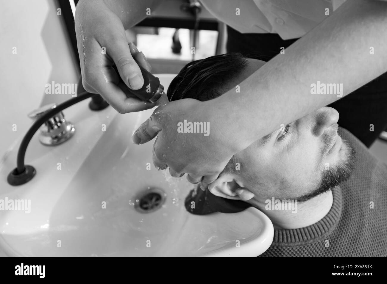 Barber shampooing washing a male client's head in the sink. Stock Photo