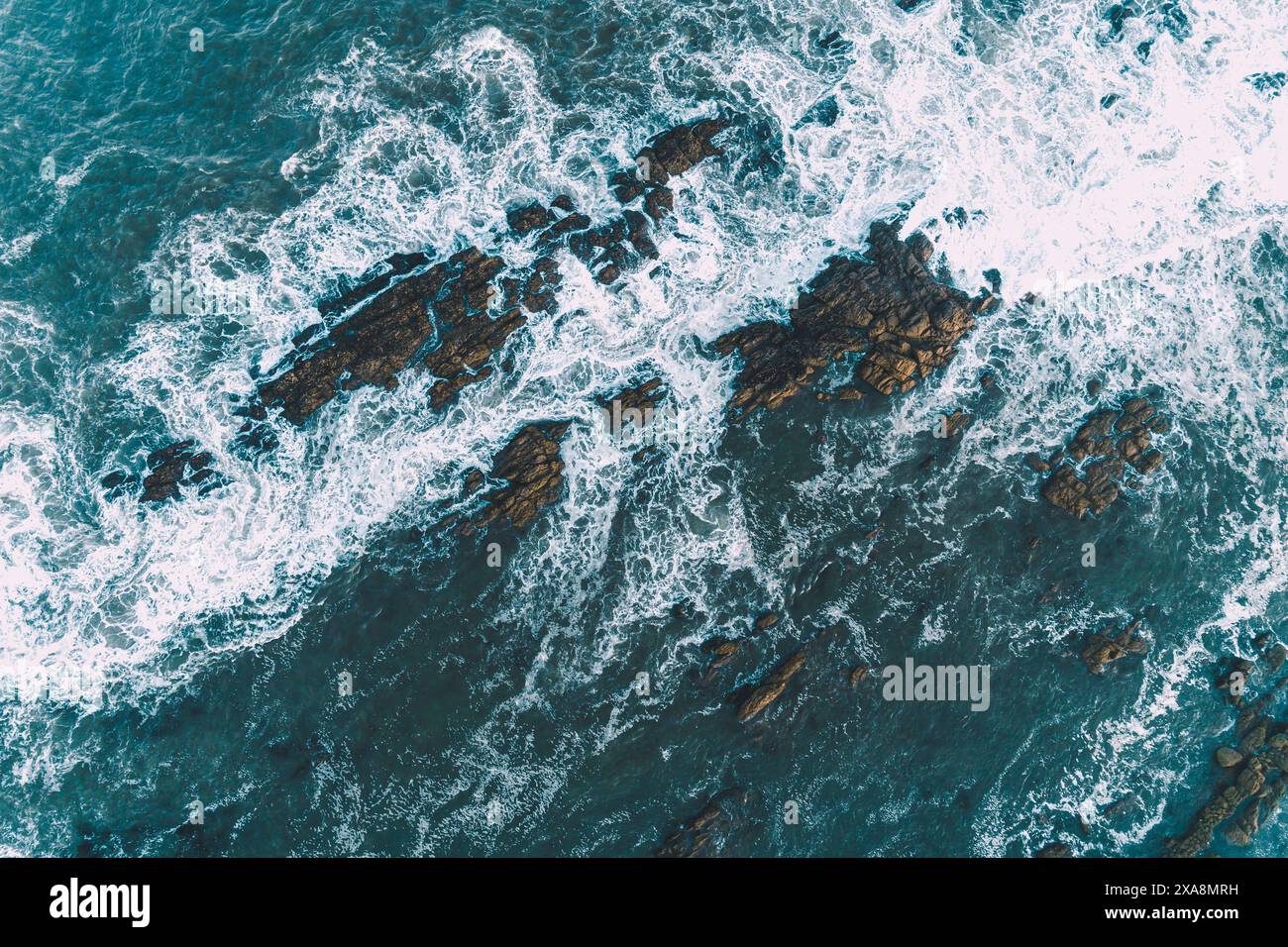 foam of the waves on the shore of a rocky coast, aerial overhead view with drone Stock Photo