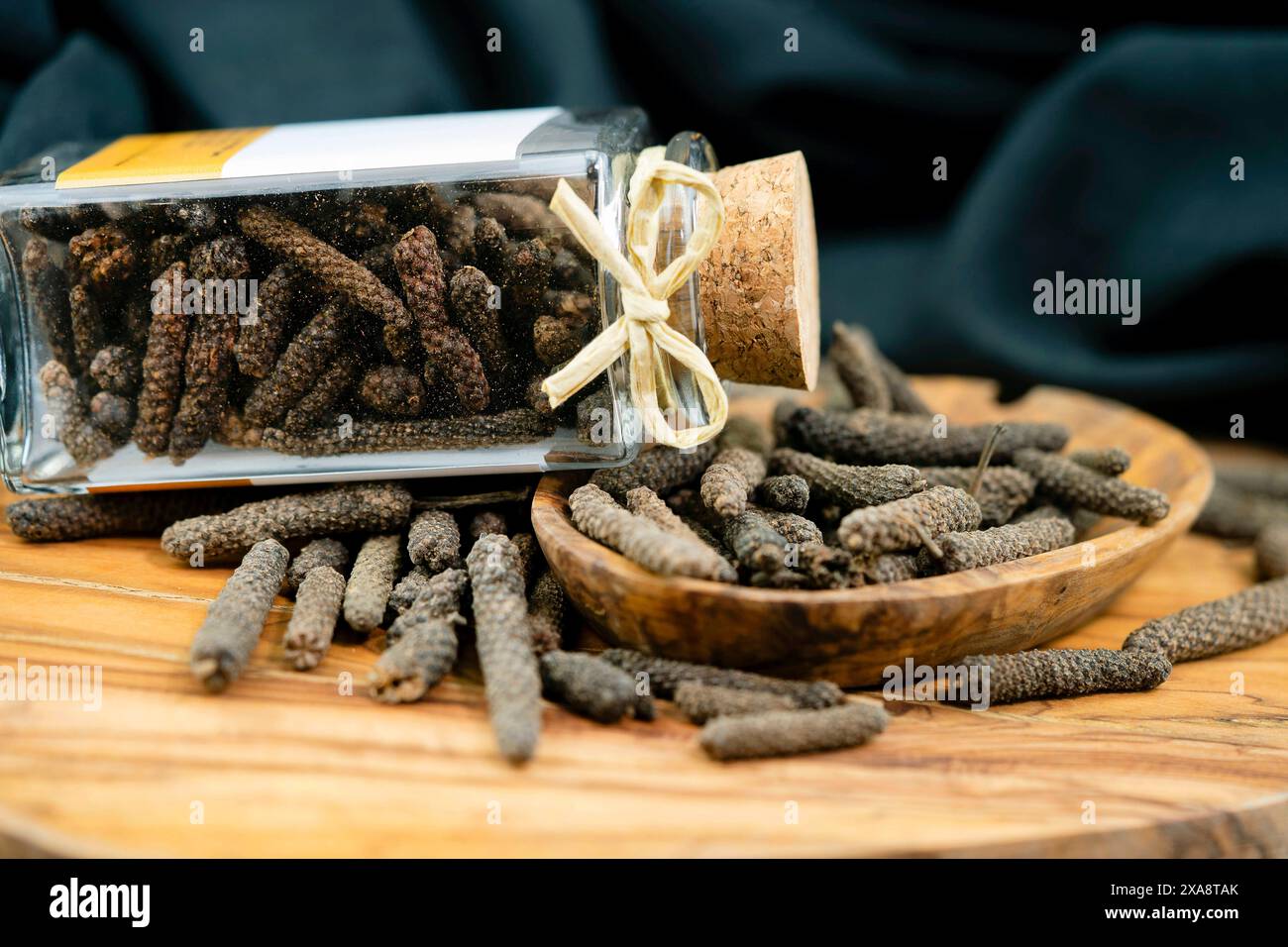 long pepper (Piper longum), on wooden plate with glass Stock Photo