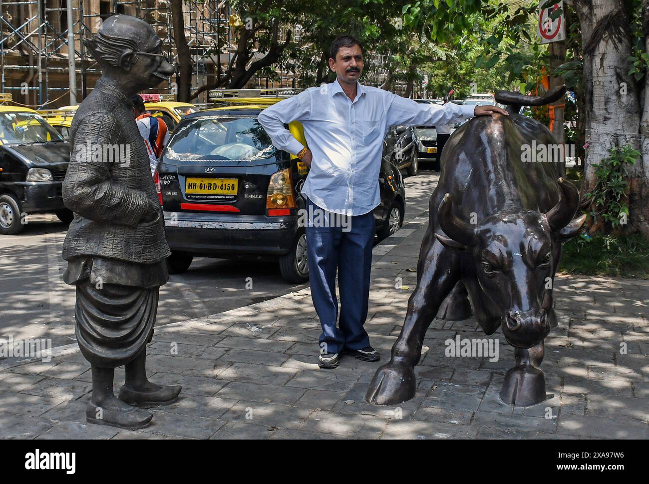 A man poses for a photo next to the statue of the bull near the Bombay Stock Exchange (BSE) building. The stock market was volatile when it opened in the morning due to election result, there was an anticipation of Bharatiya Janata Party (BJP) getting the majority of the votes and Prime Minister Narendra Modi getting elected for the third time, but that wasn't the case as opposition parties gave tough fight to the Bharatiya Janata Party (BJP) as votes were being counted and result was flashed on the screen which impacted the stock trading heavily. Stock Photo