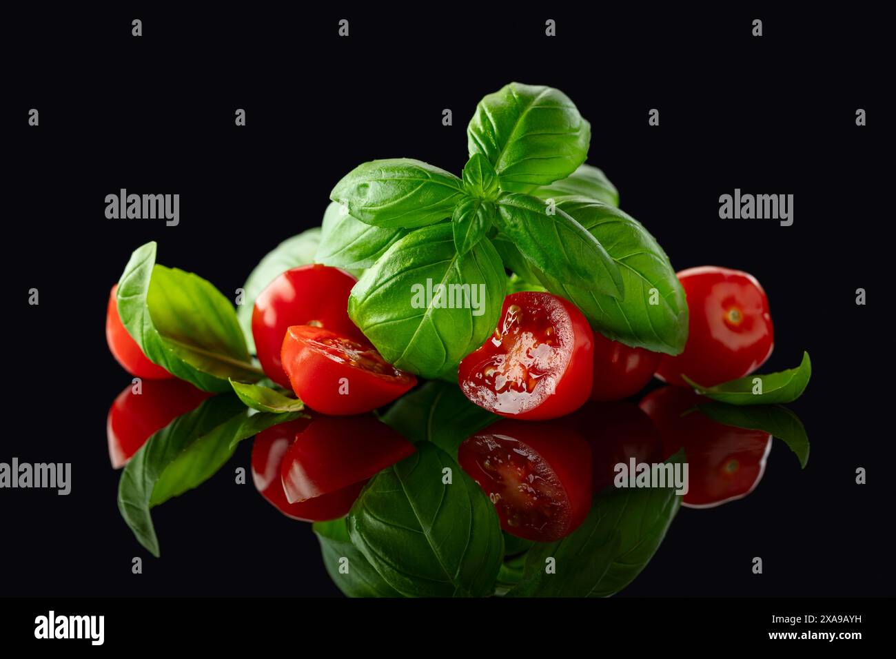 Tomatoes cherry with basil on a black reflective background Stock Photo ...