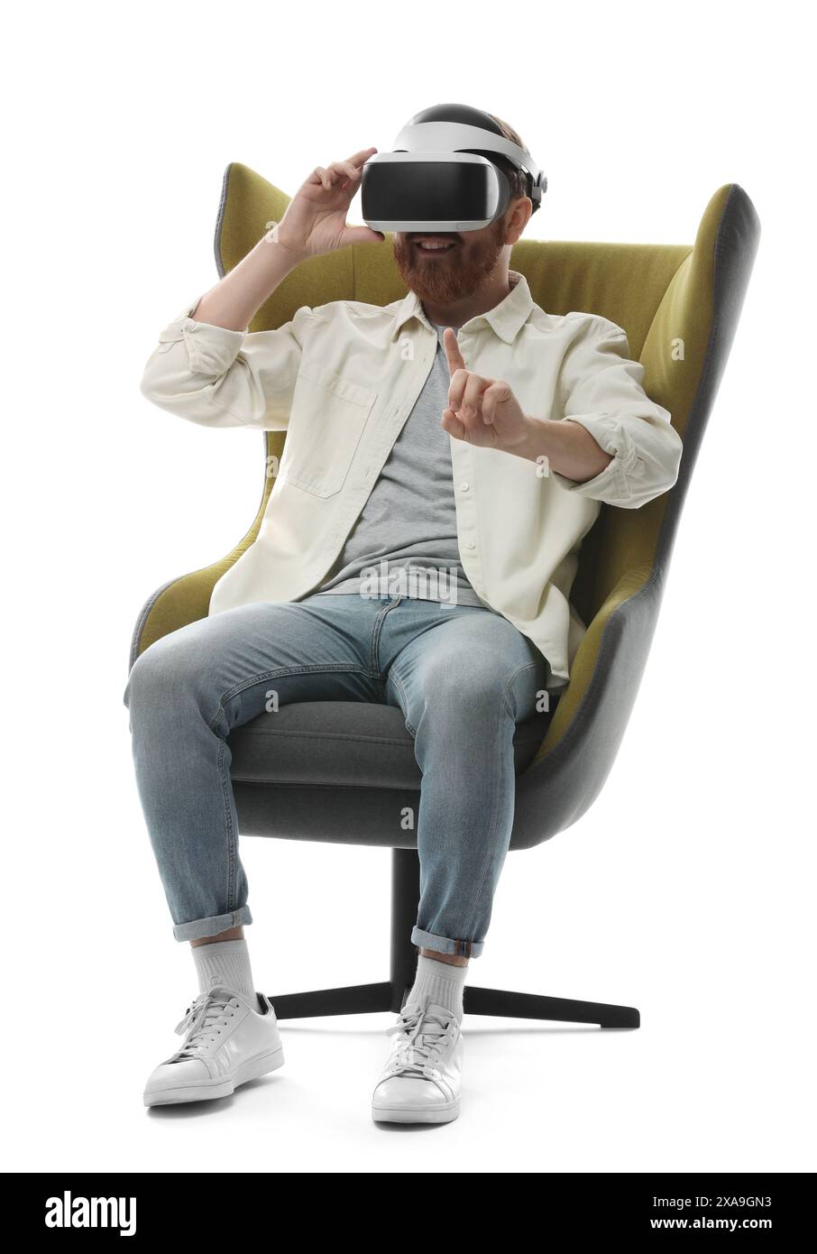 Man using virtual reality headset while sitting in armchair on white ...