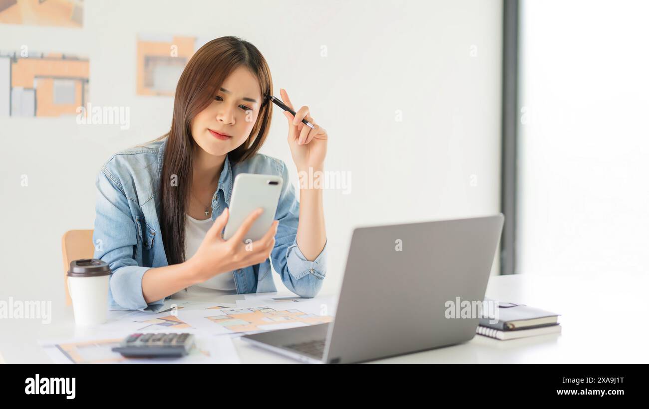 Construction design concept, Female architect using smartphone during thoughtful about house plan. Stock Photo