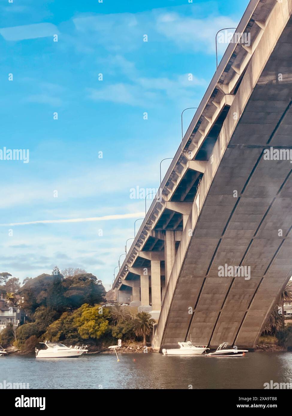 A boat passing under Gladesville Bridge in Sydney Stock Photo