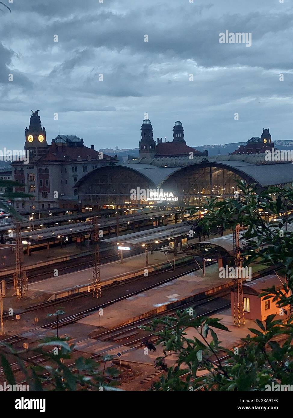 A train depot with departing train, clock tower in distance Stock Photo