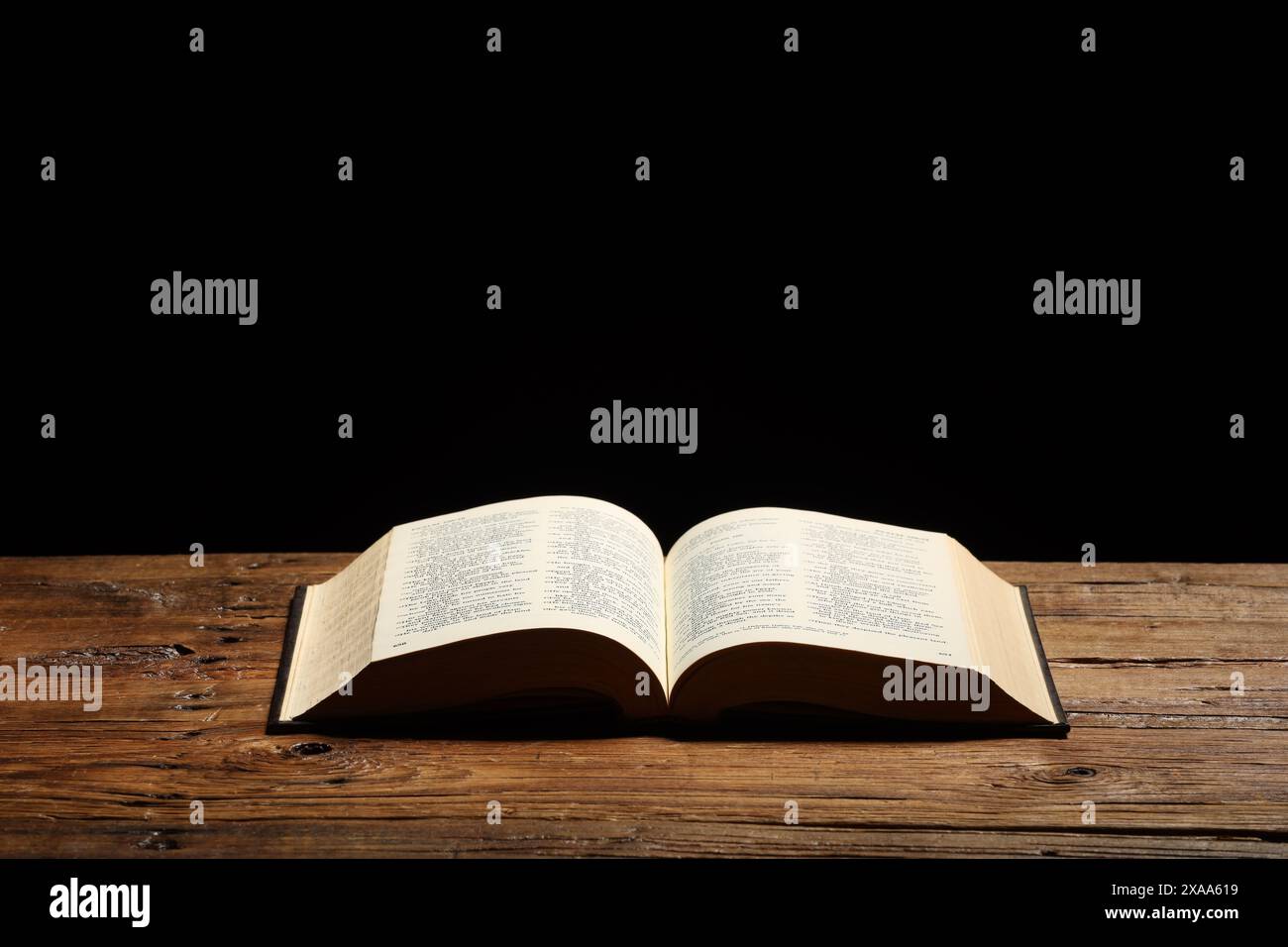 Bible on wooden table against black background, space for text. Religion of Christianity Stock Photo