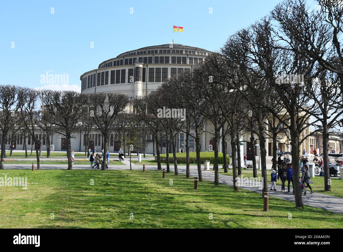 The people stroll by trees near Centennial hall in Wroclaw on a sunny day Stock Photo