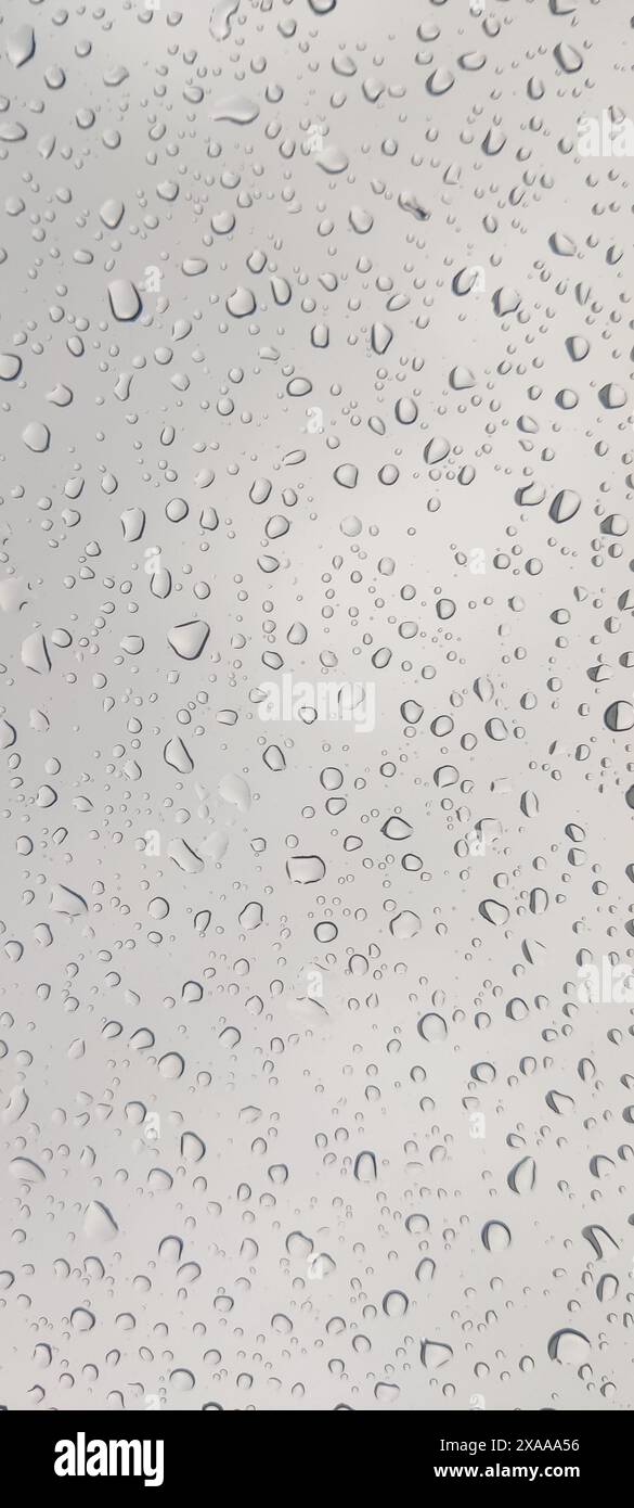 Raindrops on car windshield seen through window in close-up view Stock Photo