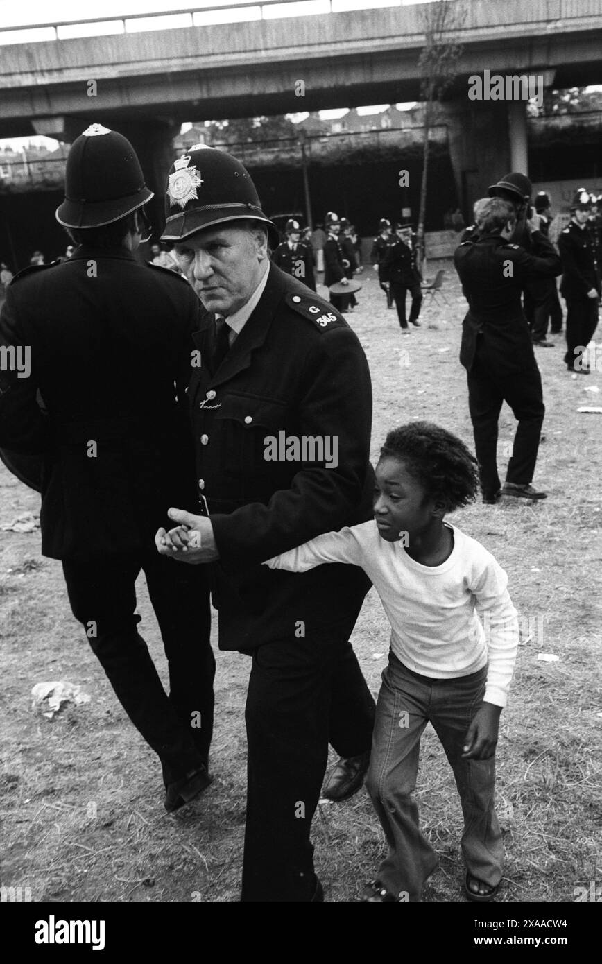 1970s Notting Hill carnival riot August Bank Holiday Monday 1976. A young scared black British child is led away to safety by a police officer, she has been separates from her family during the rioting. Notting Hill, London, England UK HOMER SYKES. Stock Photo