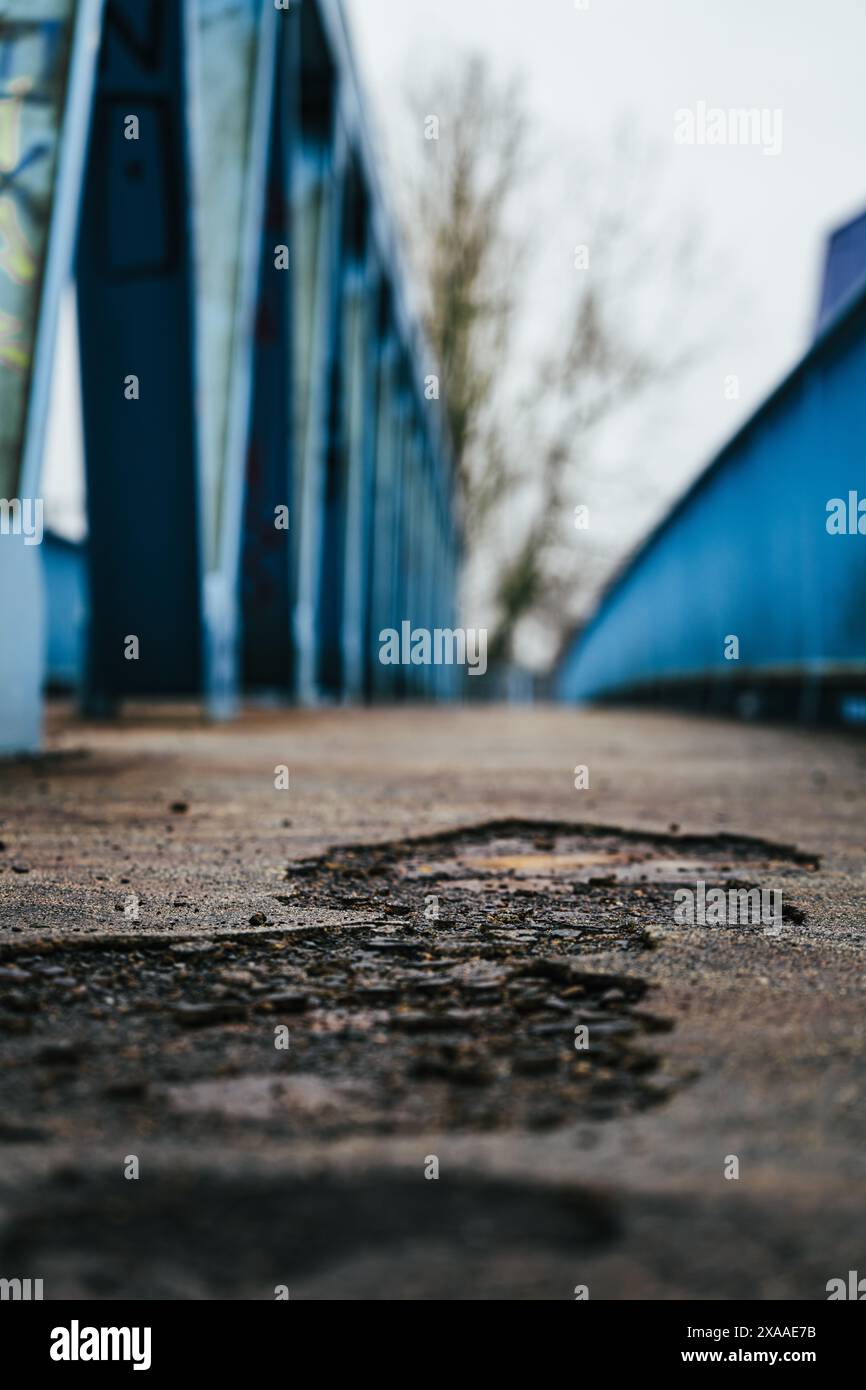 A closeup shot of holes on asphalt with bridge railing in the background Stock Photo