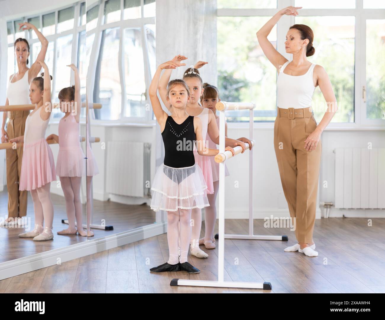Woman teacher corrects group of girls in first position Stock Photo - Alamy