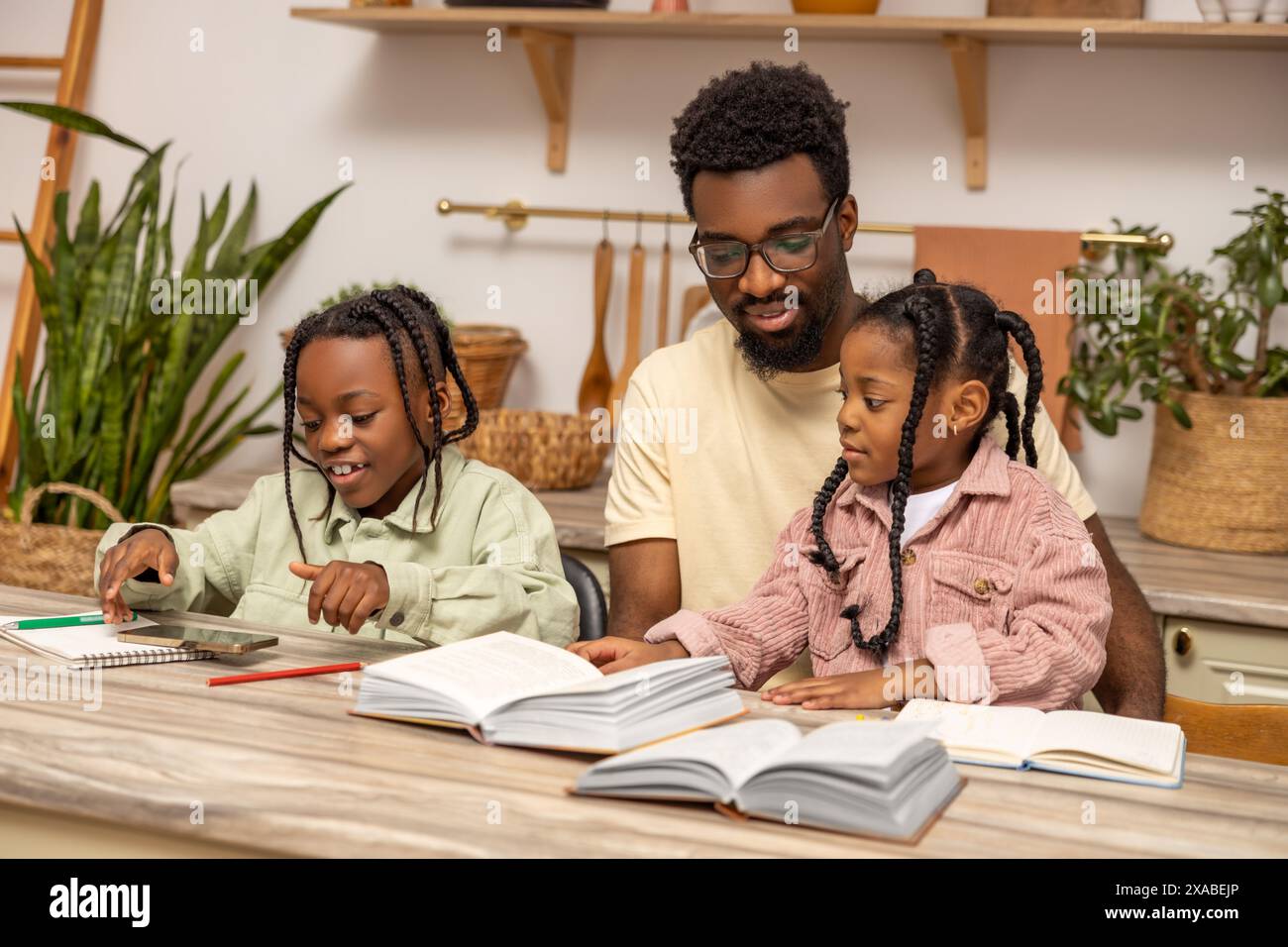 Young multiethnic father helping his daughters with homework Stock ...