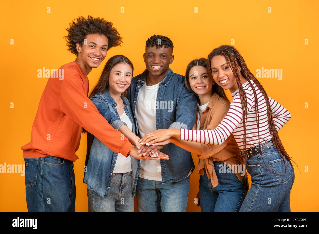 Diverse Group of Friends Stacking Hands Together in Studio Stock Photo