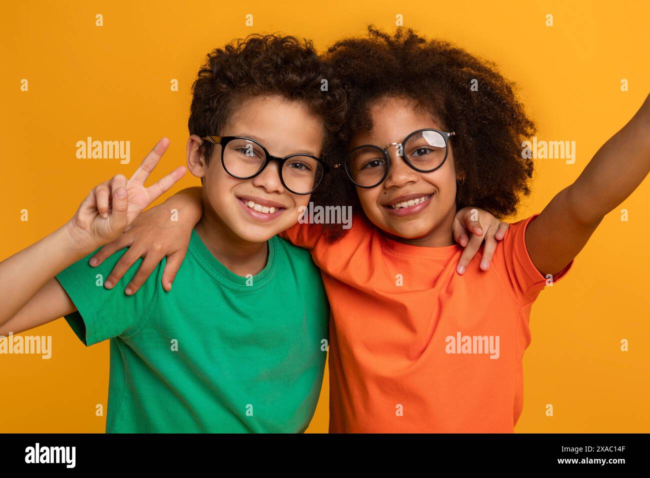 Two Smiling Kids Posing For Photo In Front Of Yellow Stock Photo - Alamy
