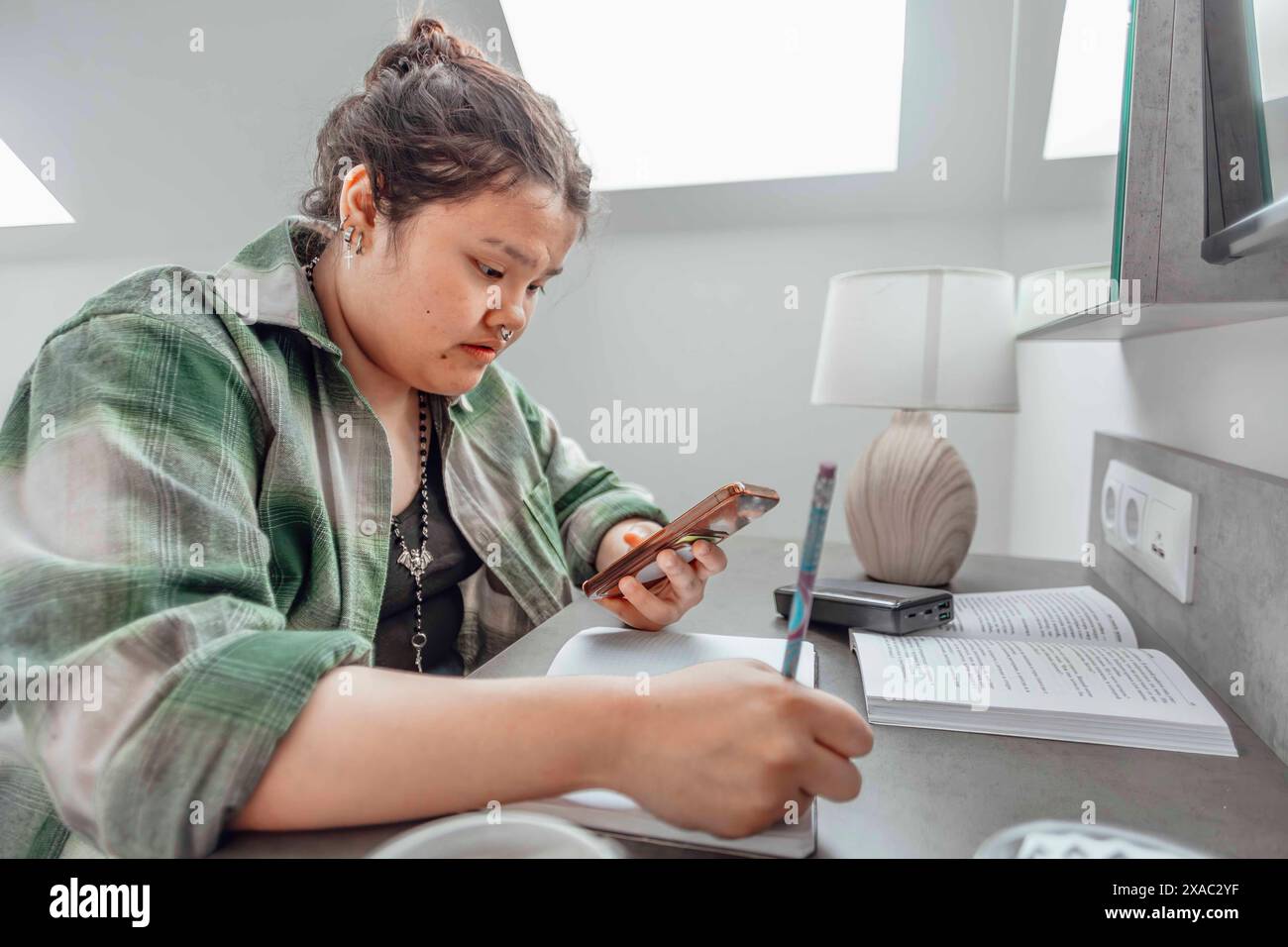 asian student juggles between her phone and handwritten notes ...