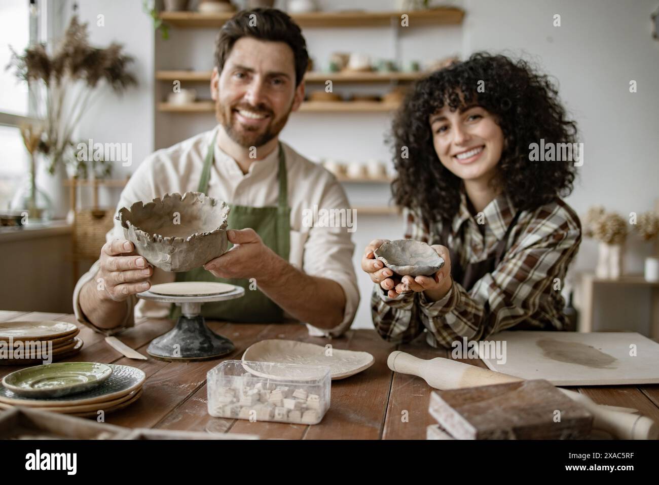 Bearded mature man and woman sculpting pottery in studio. Male sculpts ...