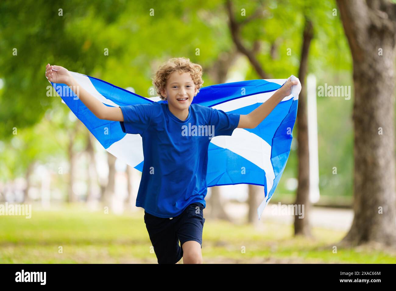 Child running with Scotland flag. Scotland football supporter kid. Scottish fan national jersey cheering for victory. Championship game. Go Scotland Stock Photo