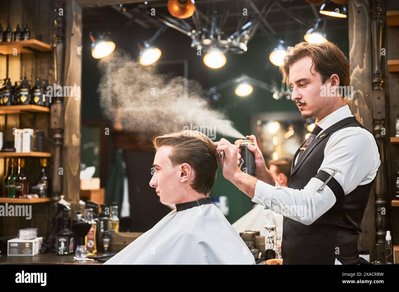 Professional barber using hairspray styling hi-res stock photography ...