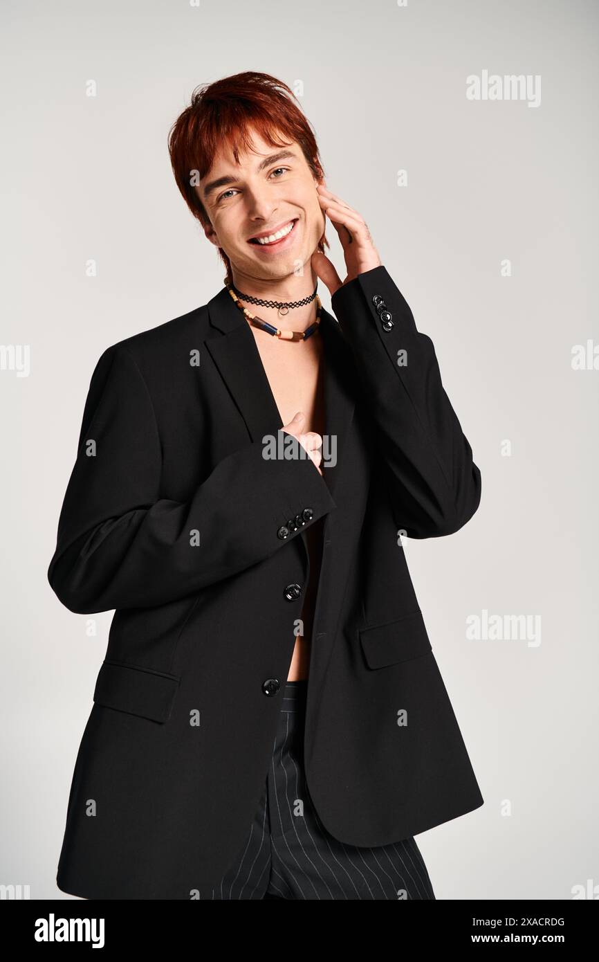 A stylish young man in a suit and tie confidently poses against a grey ...
