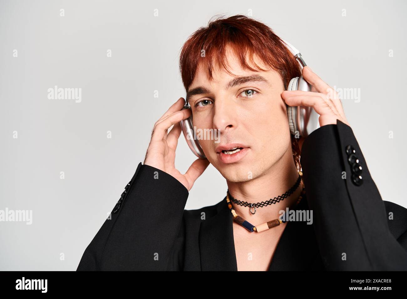 A stylish young man with red hair wearing a black suit and holding a ...
