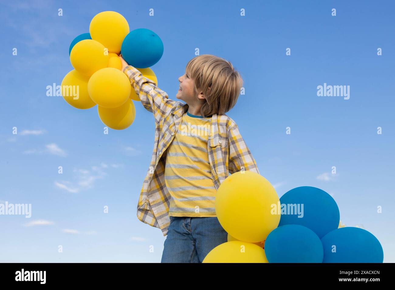 boy with blue and yellow balls in his hands on the background of the sky. stop the war in Ukraine. happy childhood. stand with Ukraine. good mood, bir Stock Photo