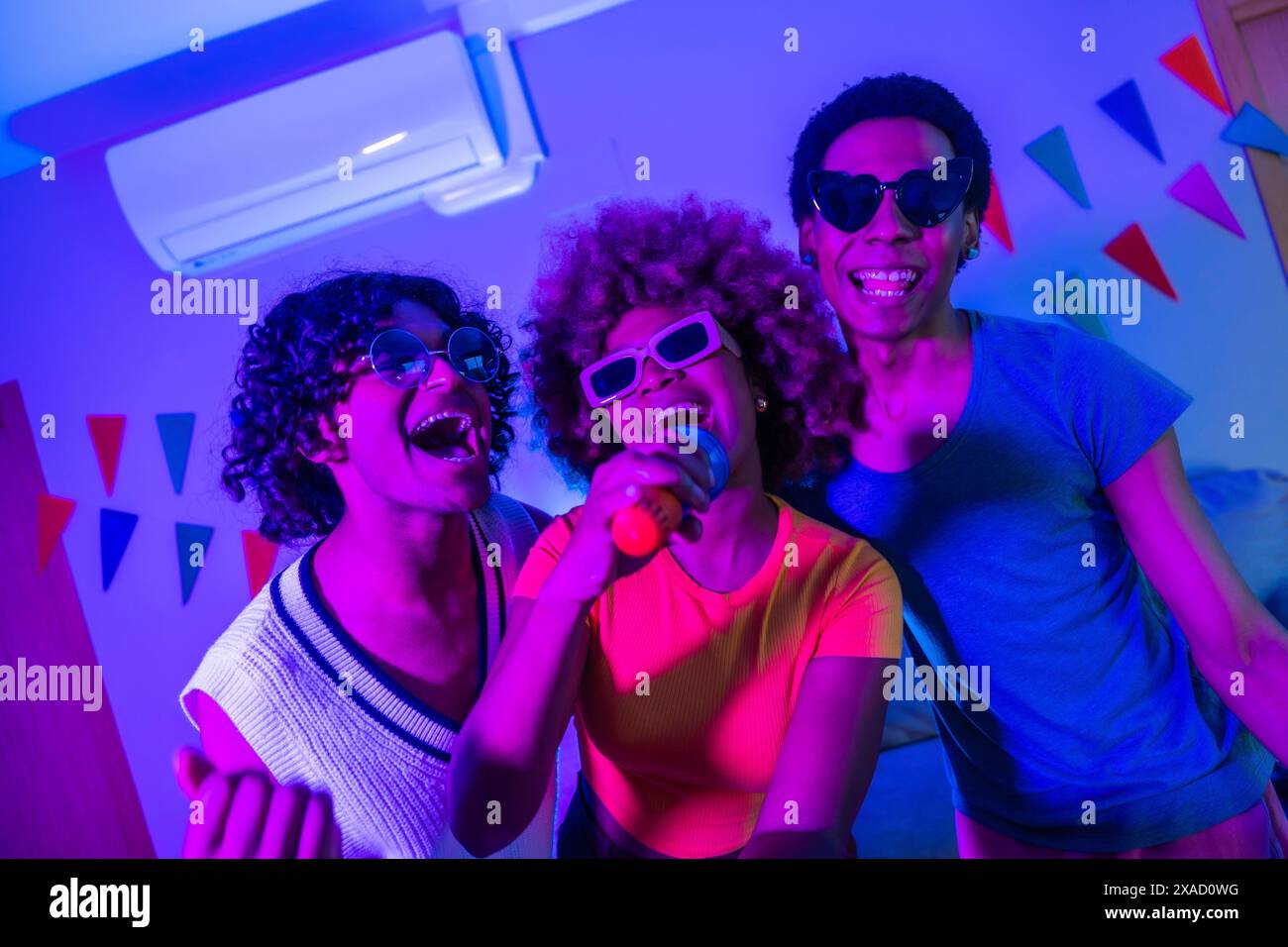 Happy multi-ethnic friends singing karaoke at night partying together ...