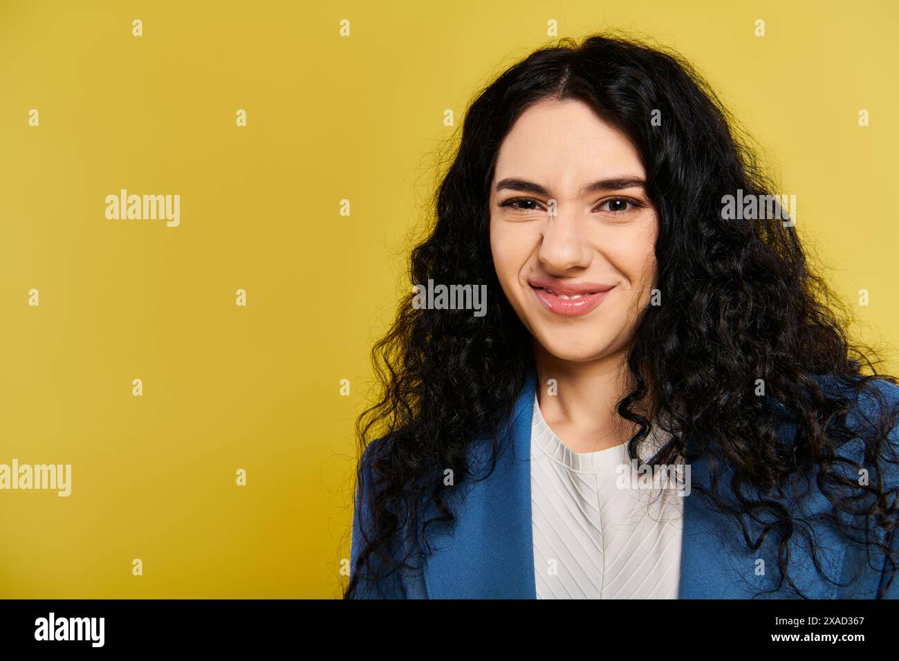 A young woman with long, curly black hair wearing a stylish blue blazer ...