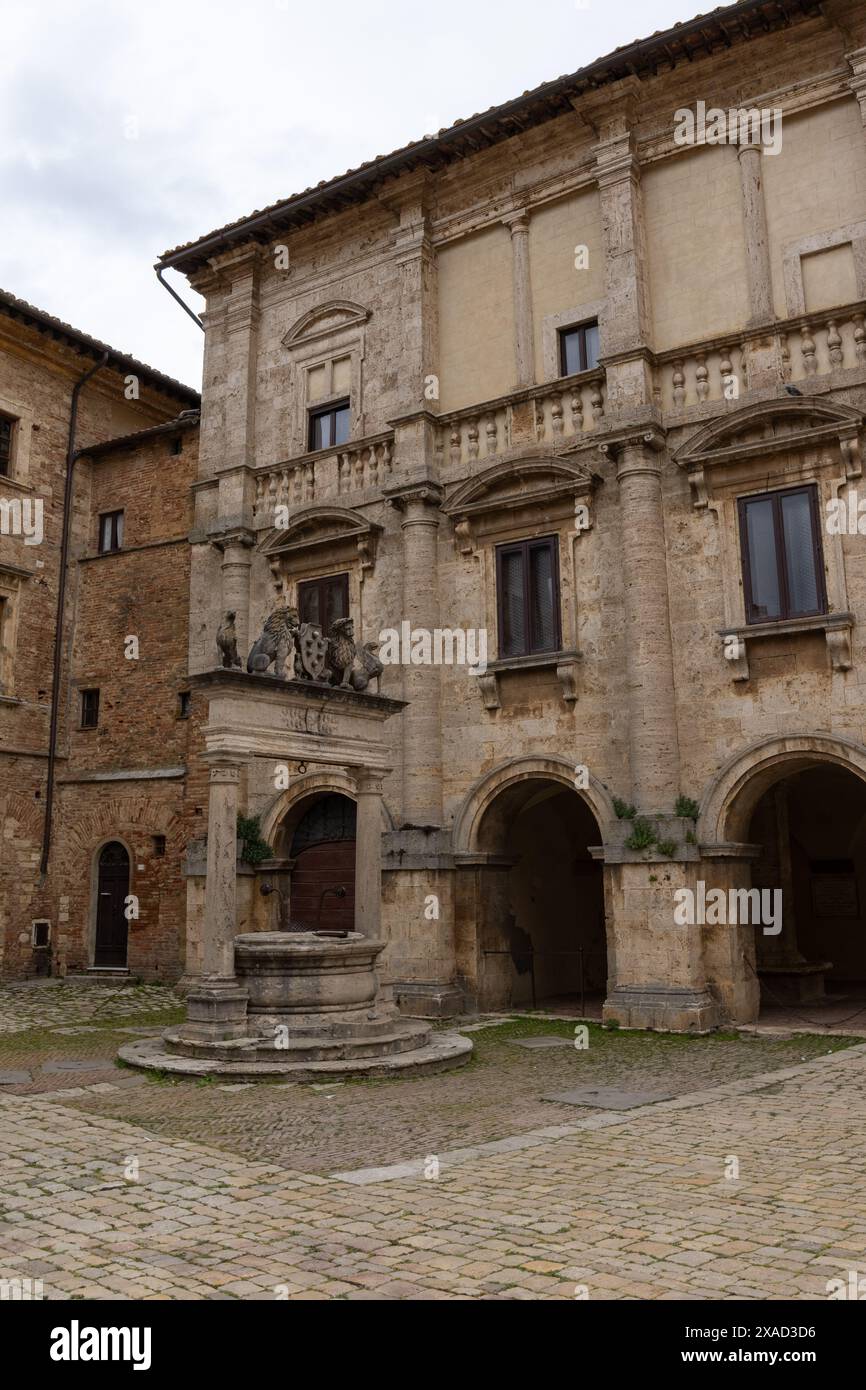 The old well in front of the Nobili-Tarugi Palace in the historic medieval city of Montepulciano in Tuscany, Italy on a cloudy day, with buildings. Stock Photo
