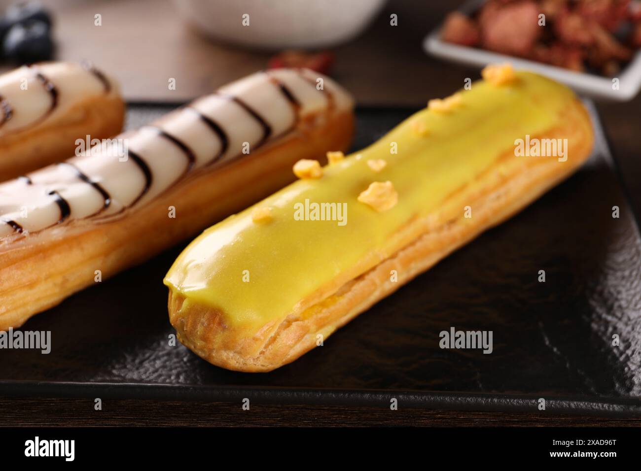 Plate with different tasty glazed eclairs on table, closeup Stock Photo