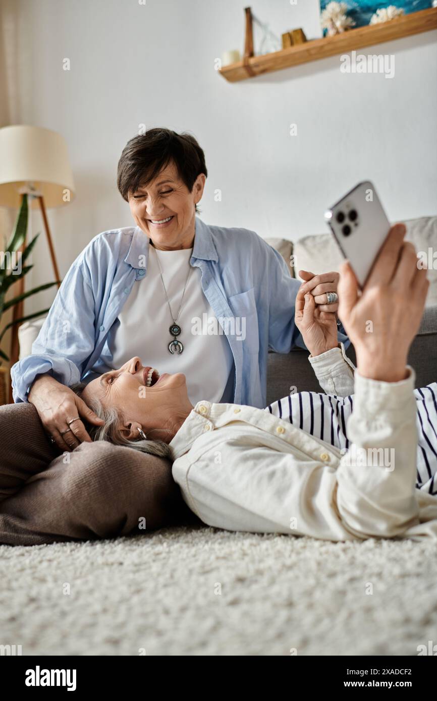 Two senior women laying on the floor, capturing a selfie moment of joy and friendship. Stock Photo