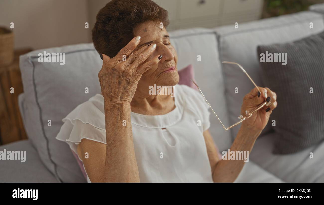 An elderly hispanic woman with short hair sits in a living room ...