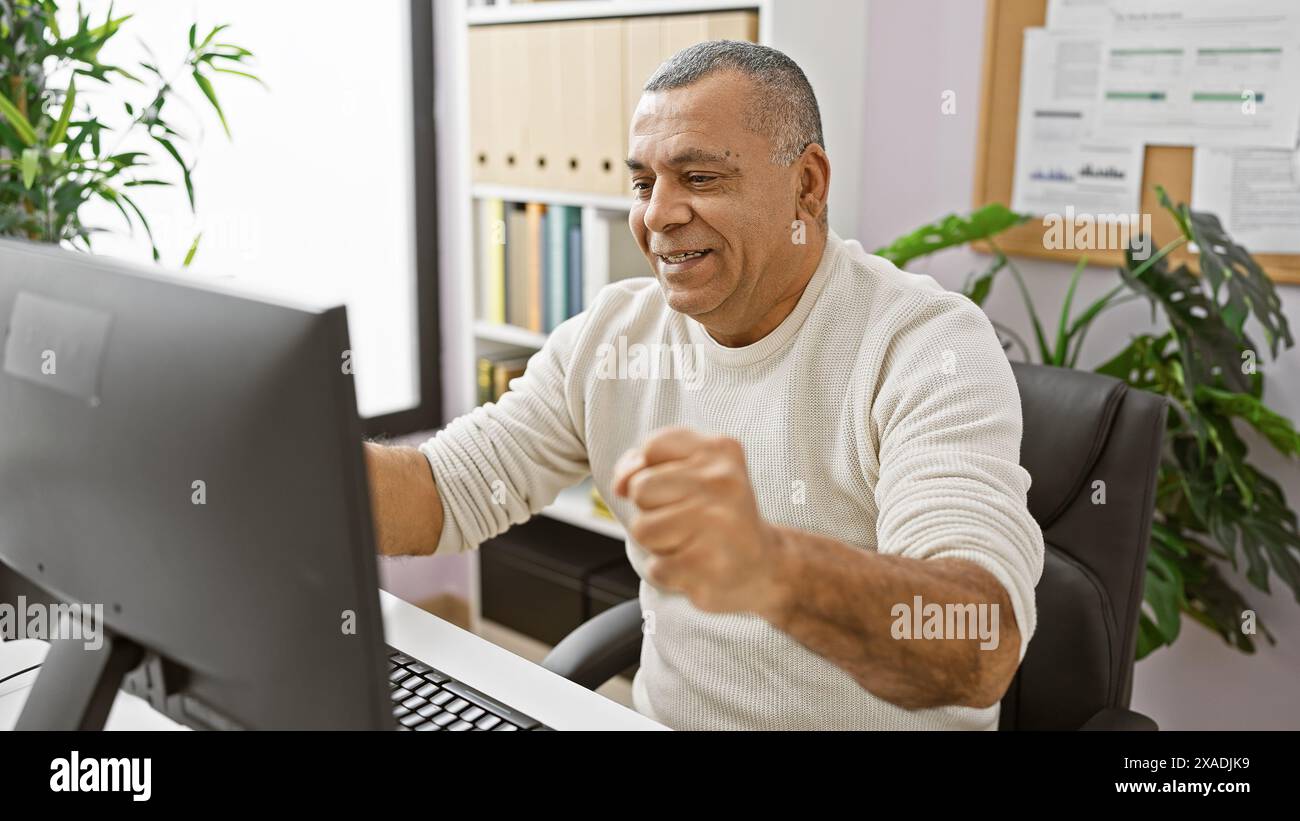 Hispanic Man Using Computer Smiling middle-aged hispanic man working on computer in modern office ...