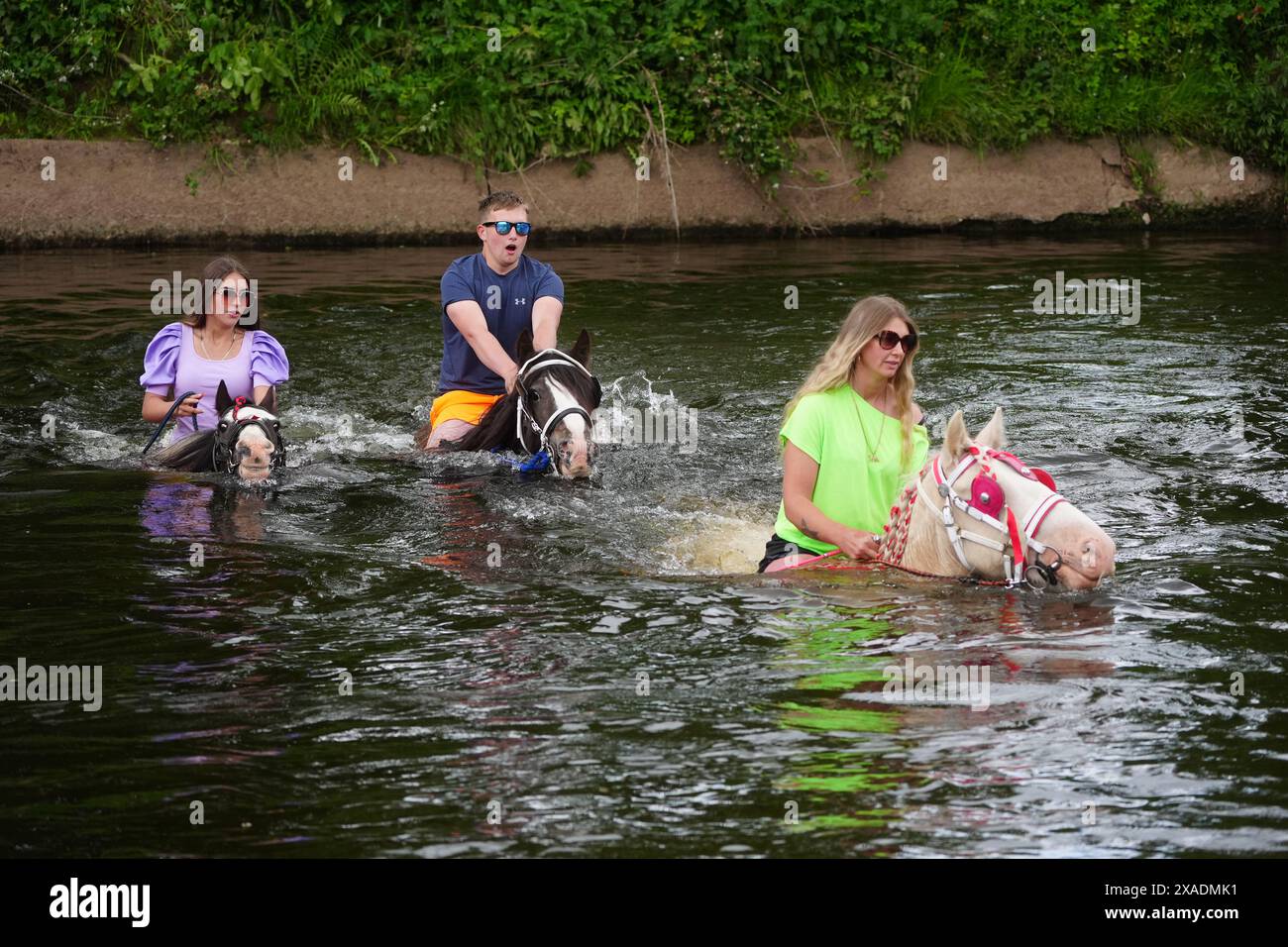 People ride horses through the river at the Appleby Horse Fair, the