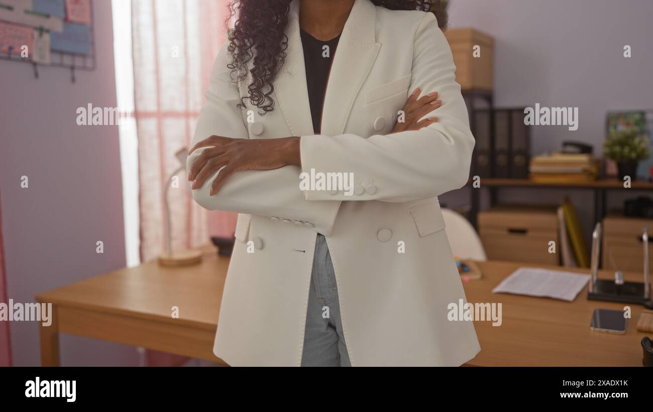 Confident african american woman standing with crossed arms in a modern detective office interior. Stock Photo