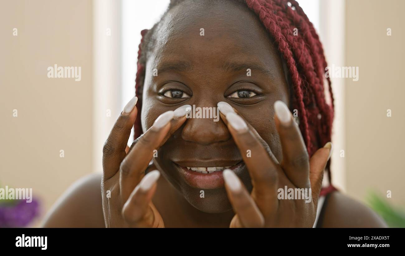 Beautiful african american woman with braids smiling indoors against a ...