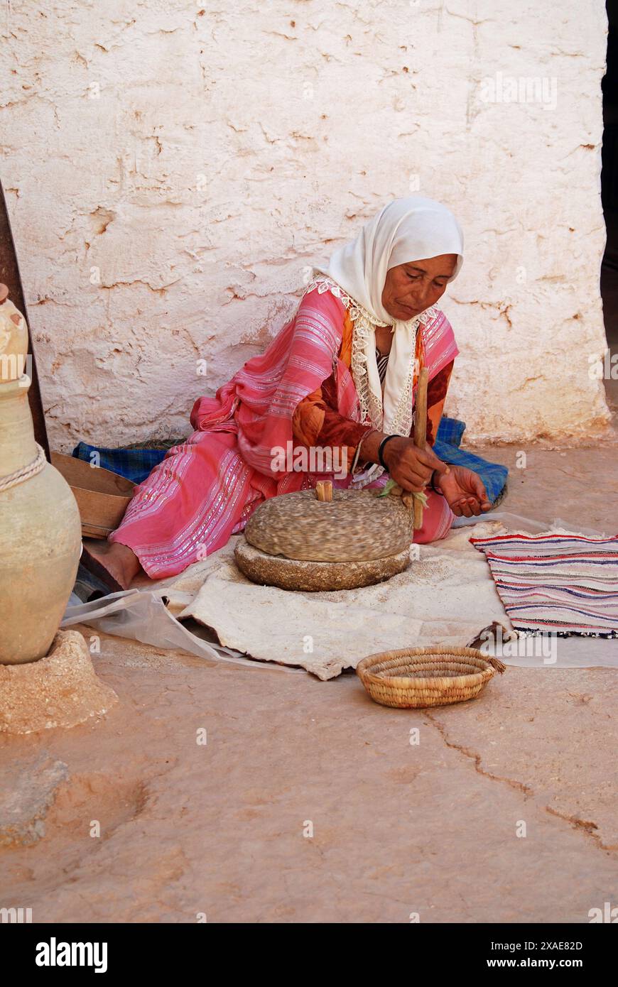 Berber Woman in Troglodyte House Grinding Corn, Matmata, Gabes Governorate, Tunisia Stock Photo