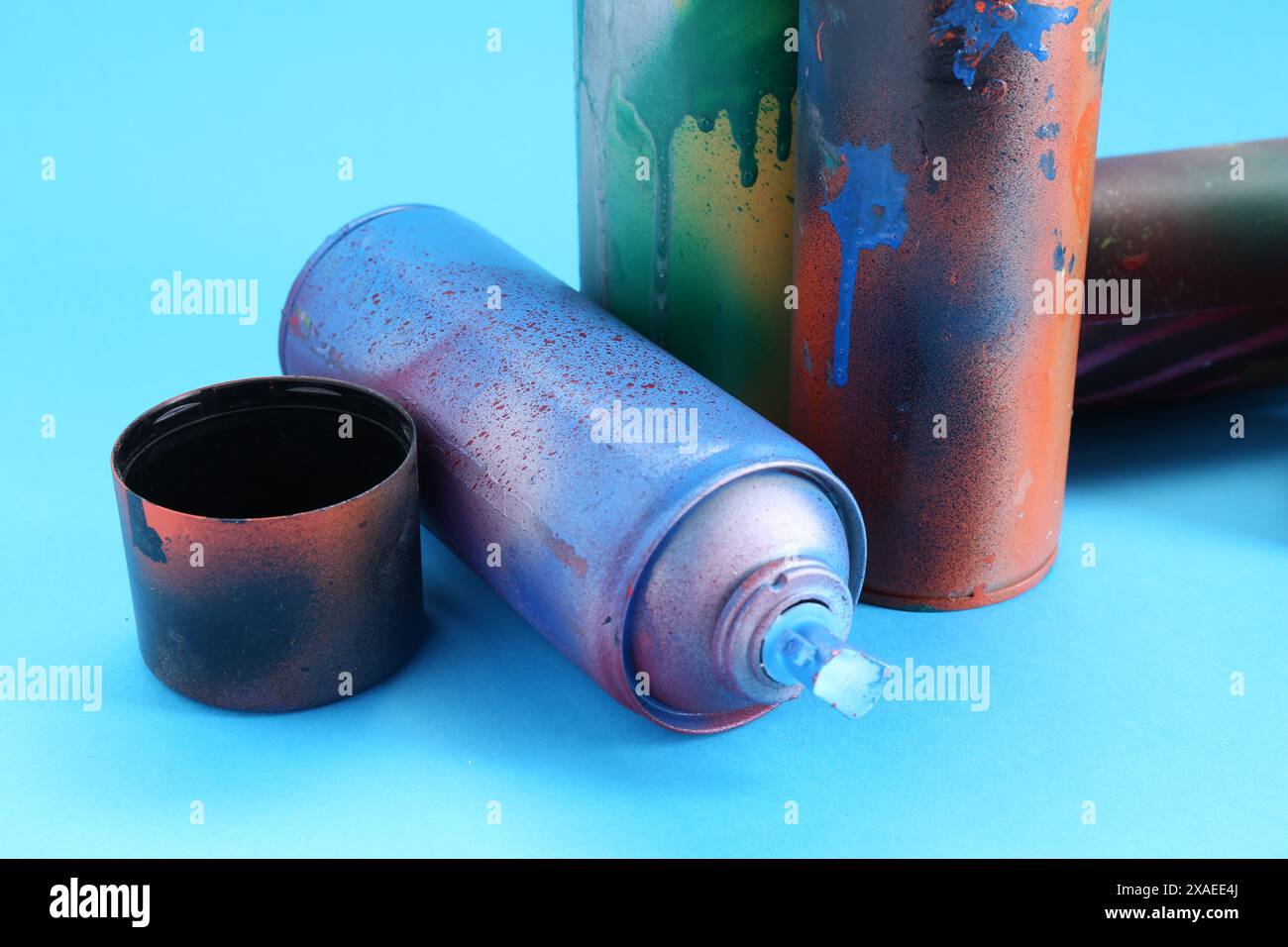 Spray paint cans and caps on light blue background Stock Photo - Alamy