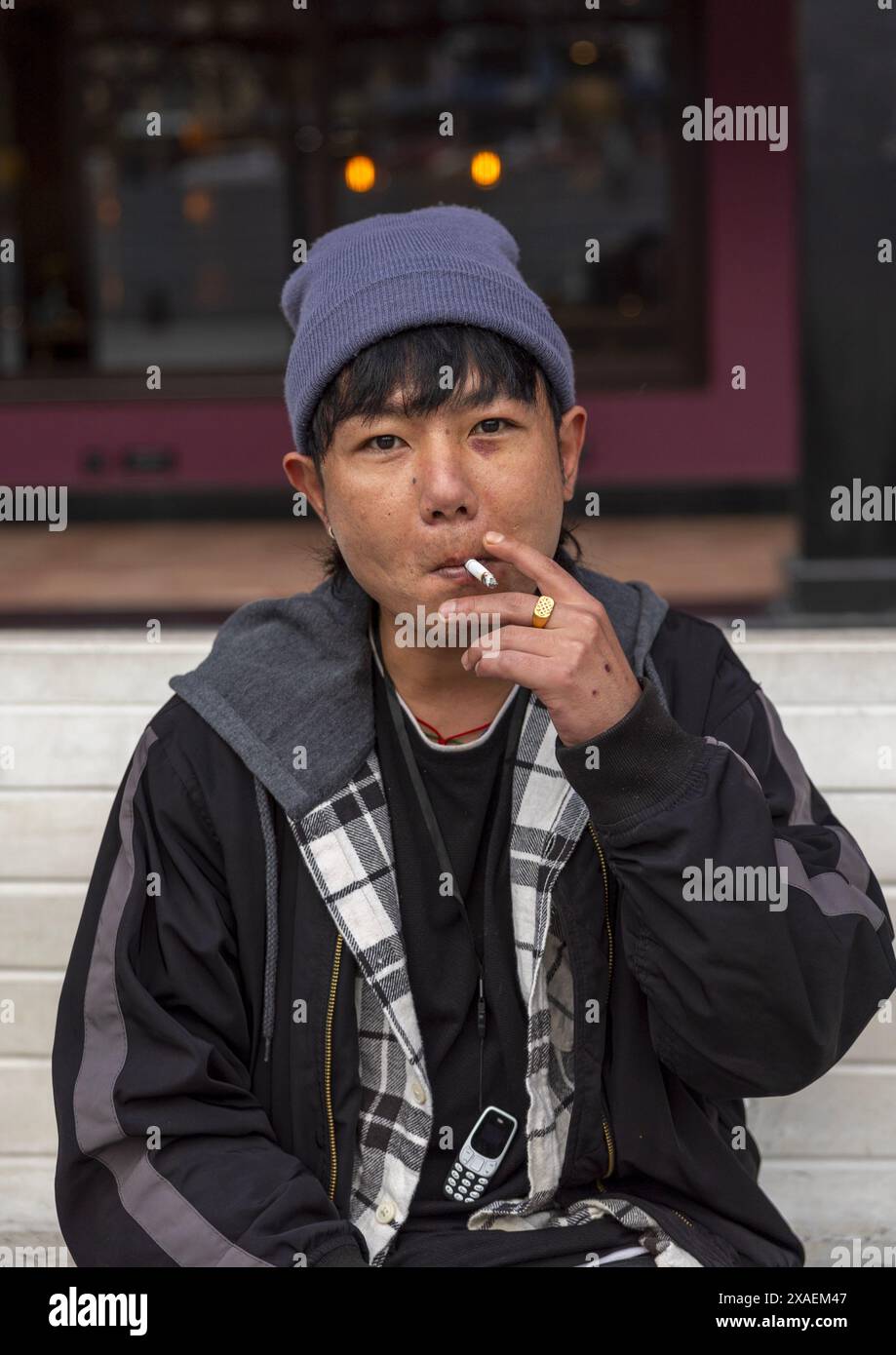 Bhutanese young man smoking cigarette in the street, Chang Gewog, Thimphu,  Bhutan Stock Photo