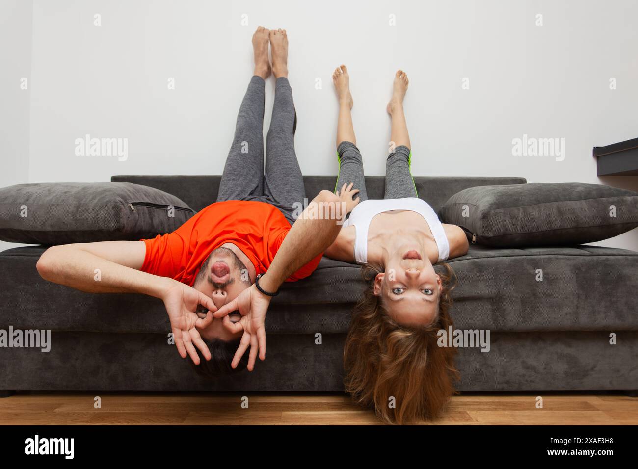 A young man and woman enjoy a fun moment hanging upside down on their ...