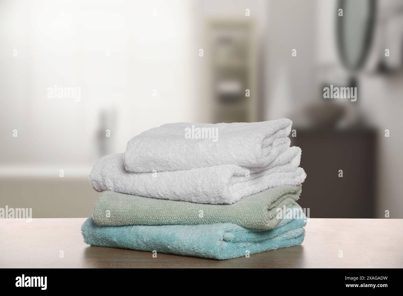 Folded fresh towels on wooden against blurred bathroom interior Stock Photo