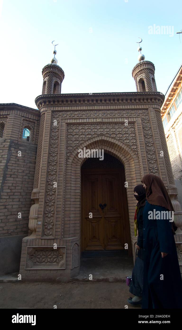 Uyghur women selling things under a small mosque in the old city in Kashgar, Xinjiang, China. Stock Photo